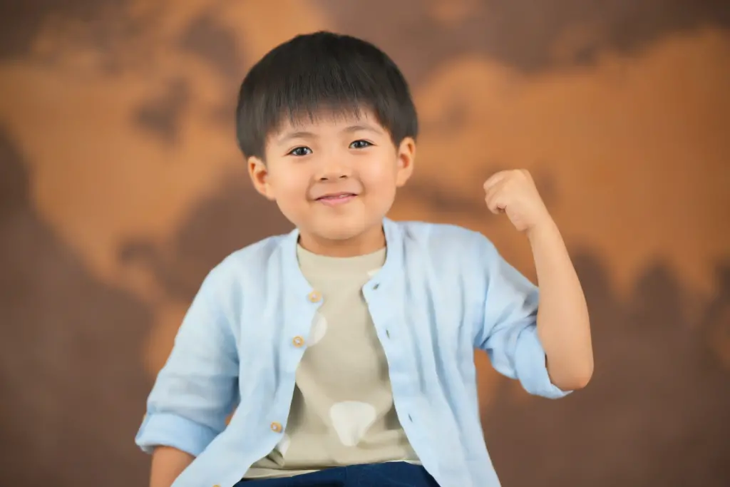 世界地図を背景にガッツポーズをする男の子