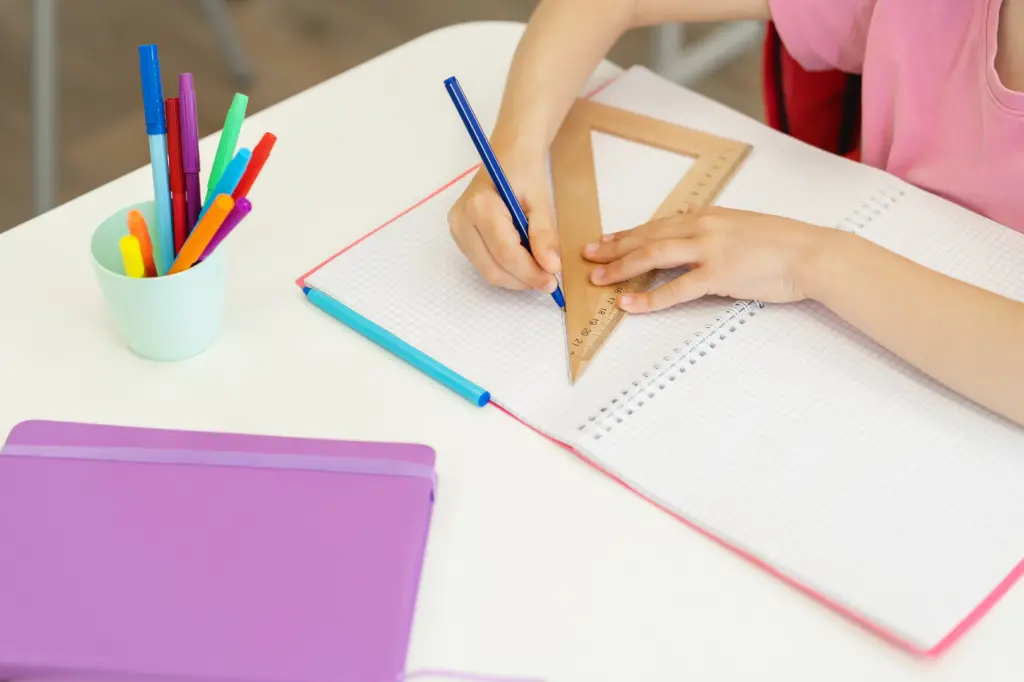 ノートに定規で線を引く子供