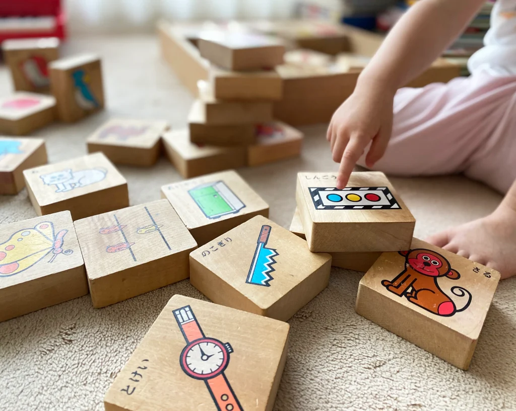 絵柄のある木製の知育玩具で遊ぶ子どもの手元
